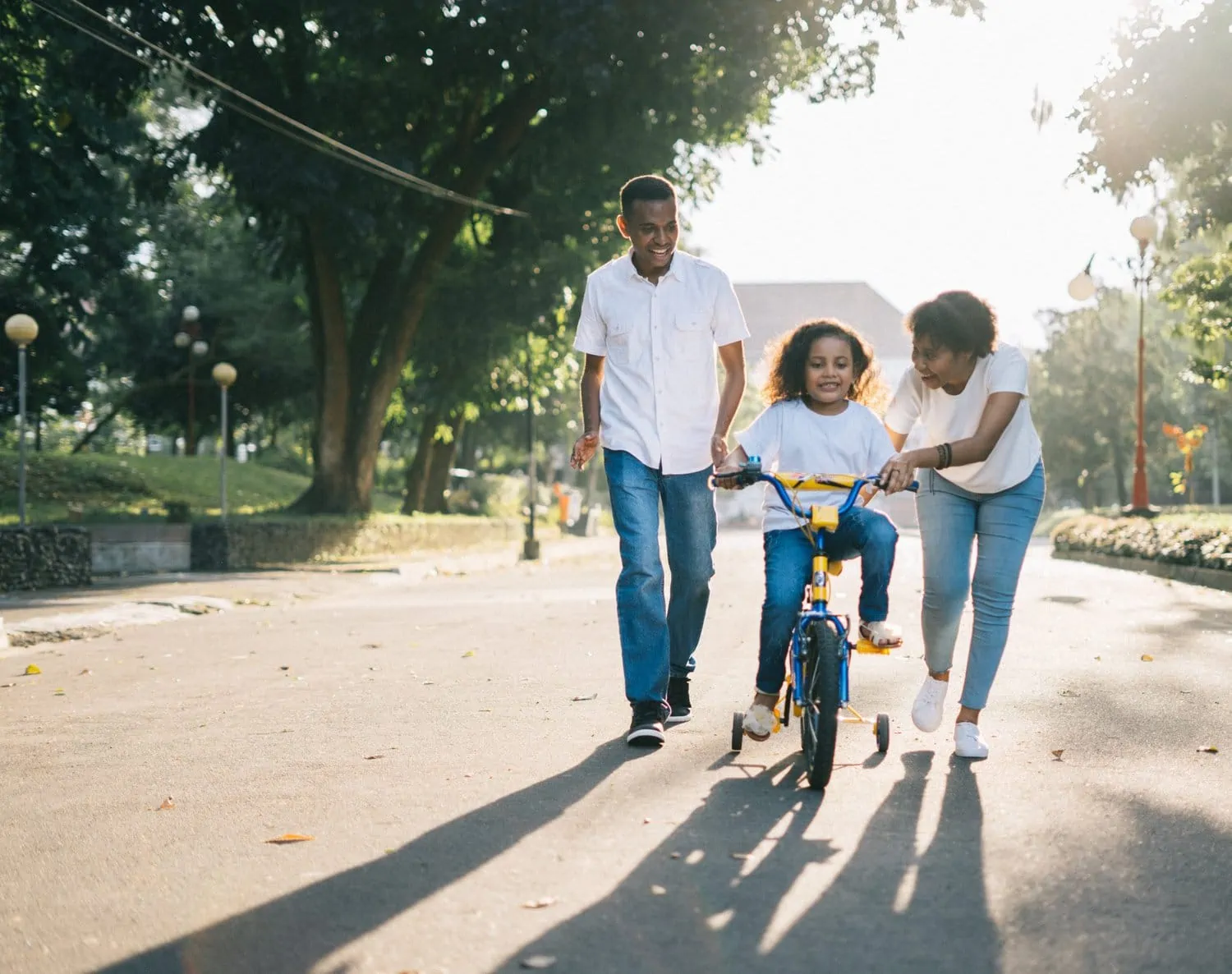 Mom and dad teaching daughter to ride a bike so their purpose is to teach