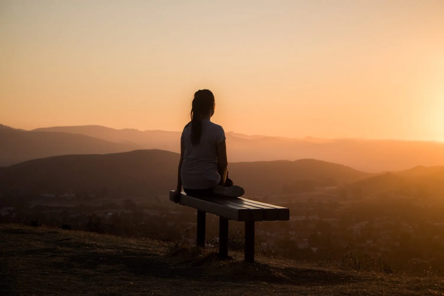 Woman sitting on bench during the sunset wondering about regrets