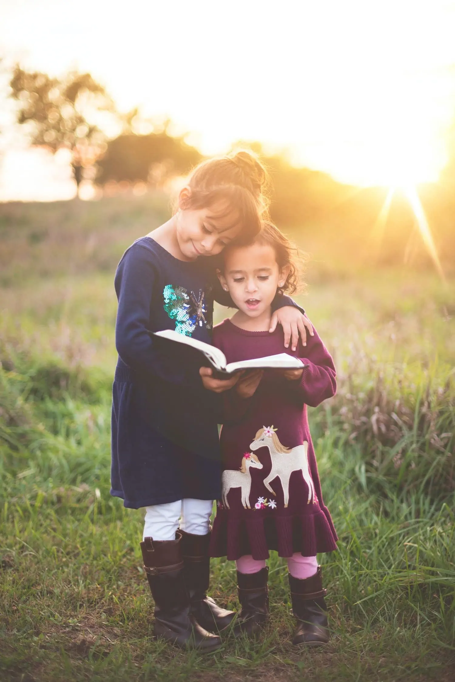 Two siblings reading a book together in the sunset, loving